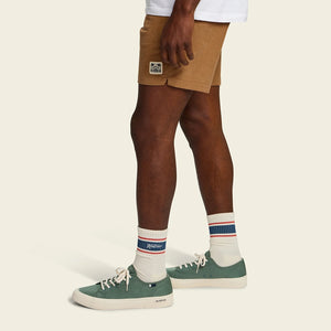 Man wearing Howler Script Socks in White with green suede sneakers, cream crew socks with navy and red stripe, lifestyle shot -- The Simple Man
