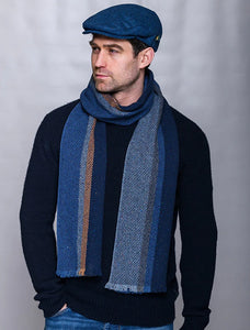 Man wearing a blue Donegal wool scarf with subtle color flecks, styled with a navy sweater and cap, photographed for The Simple Man men’s winter accessories