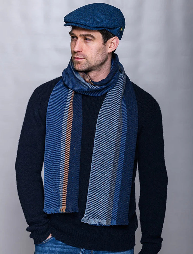 Man wearing a blue Donegal wool scarf with subtle color flecks, styled with a navy sweater and cap, photographed for The Simple Man men’s winter accessories