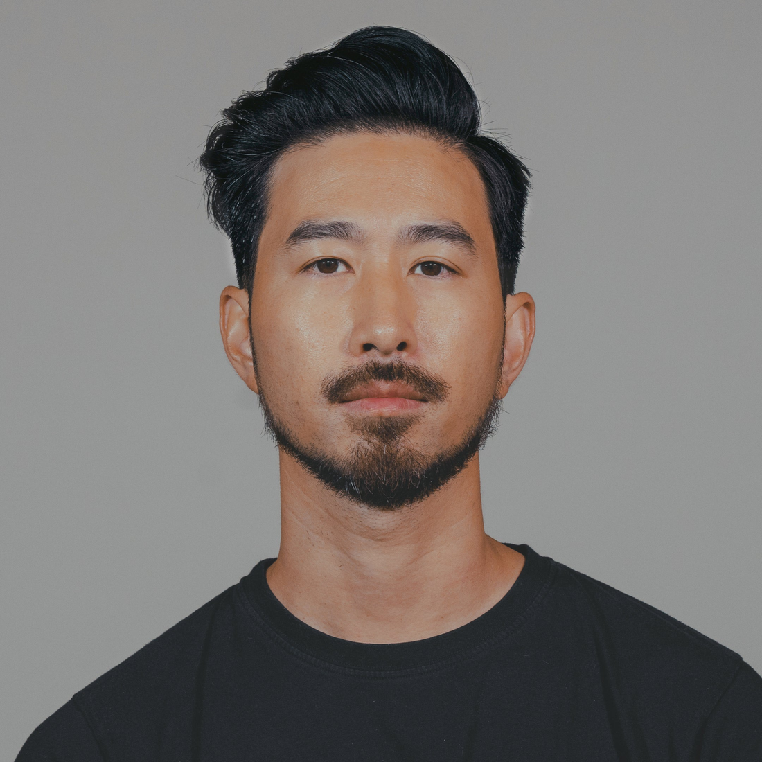 Man with a short side-swept style and trimmed beard, hair styled with Sponge Wax