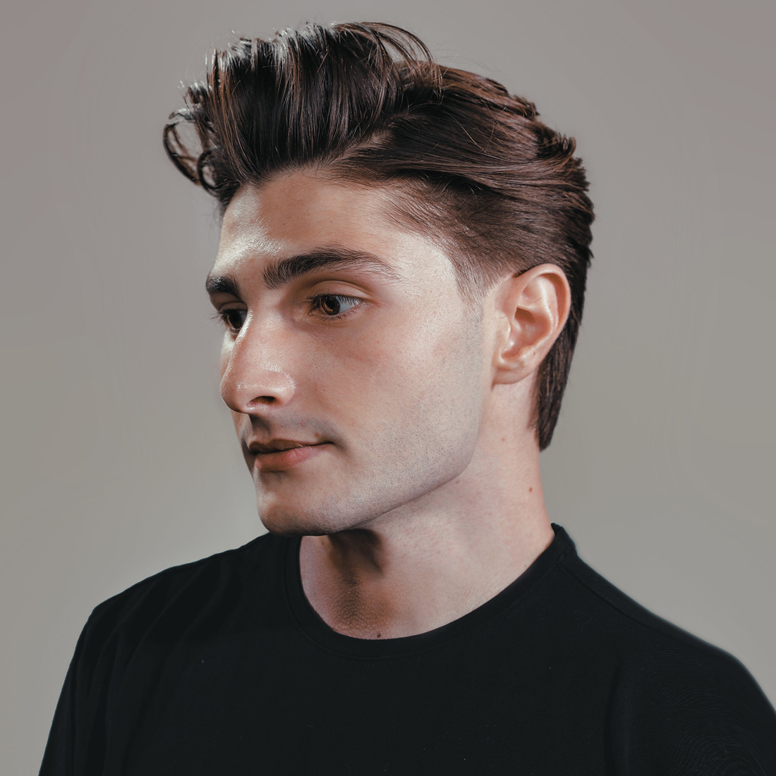Man in profile with voluminous swept-back hair, styled with Sponge Wax
