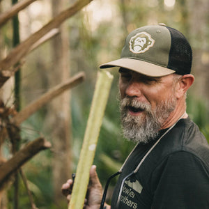 Man wearing the El Mono Standard Hat in Army/Khaki while outdoors, showing front logo and fit.