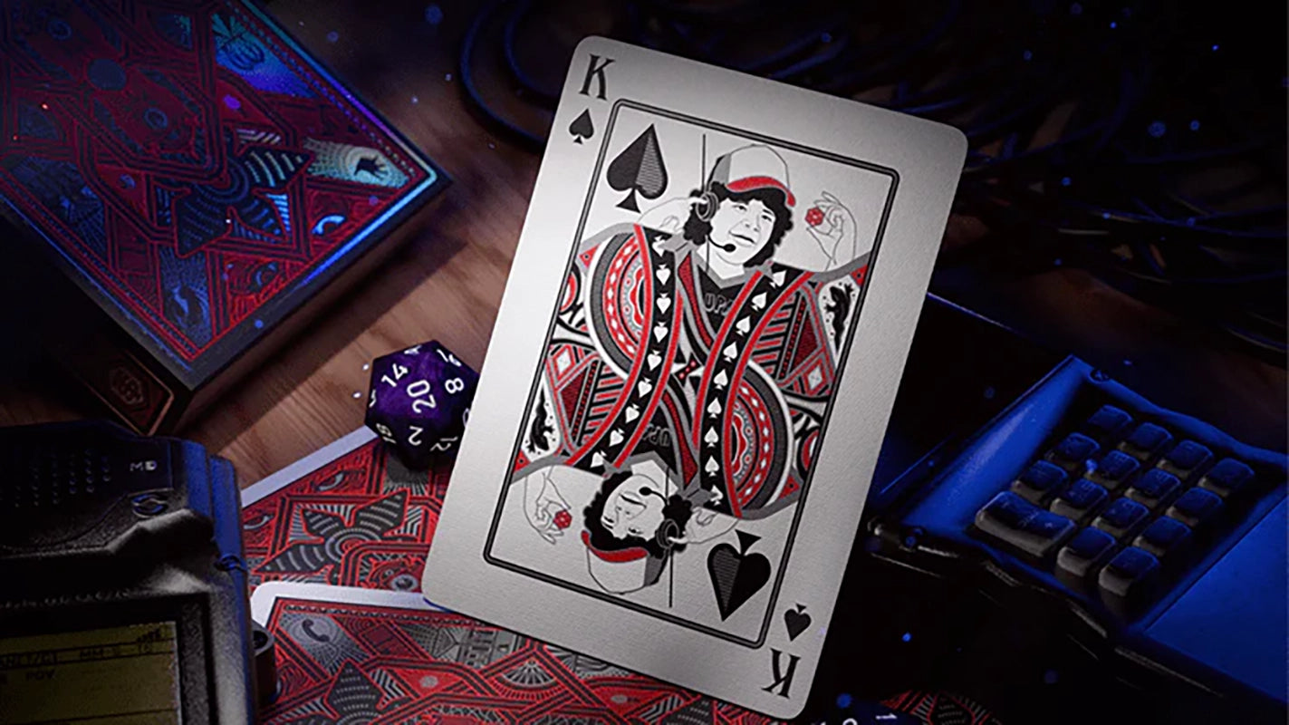 Stranger Things King of Spades card featuring Dustin from Theory11, shown with red and black card backs and gaming table accessories