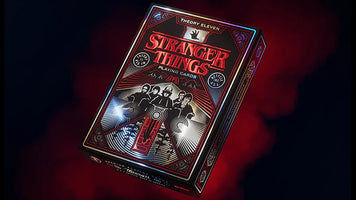 Theory11 Stranger Things playing cards deck with detailed red and black foil packaging on a smoky dark background