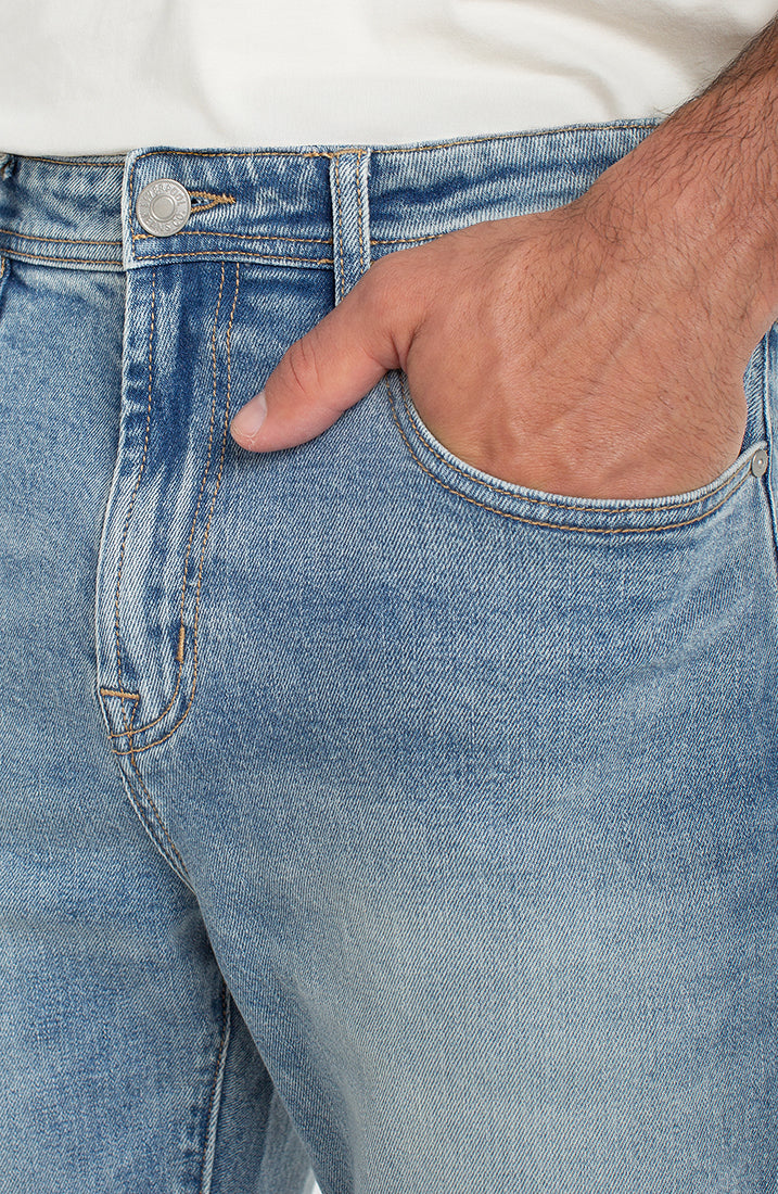 Close-up of light wash stretch denim texture and front pocket detail