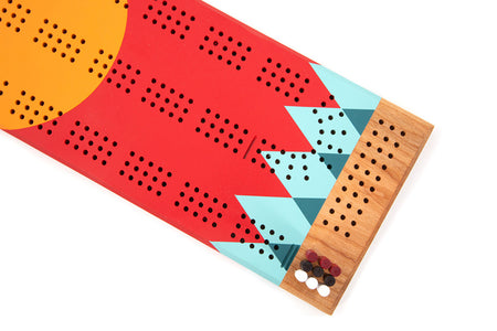 Detail of painted Tettegouche cribbage board showing teal geometric pattern and peg starting area.”