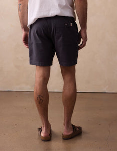 Man wearing The Normal Brand Texstretch Summer Short in Storm back view – dark charcoal 7 inch inseam cotton stretch short with sandals
