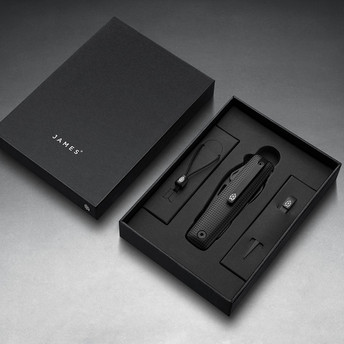 Helton in Black + Black in its box with lanyard and bead, top-down view