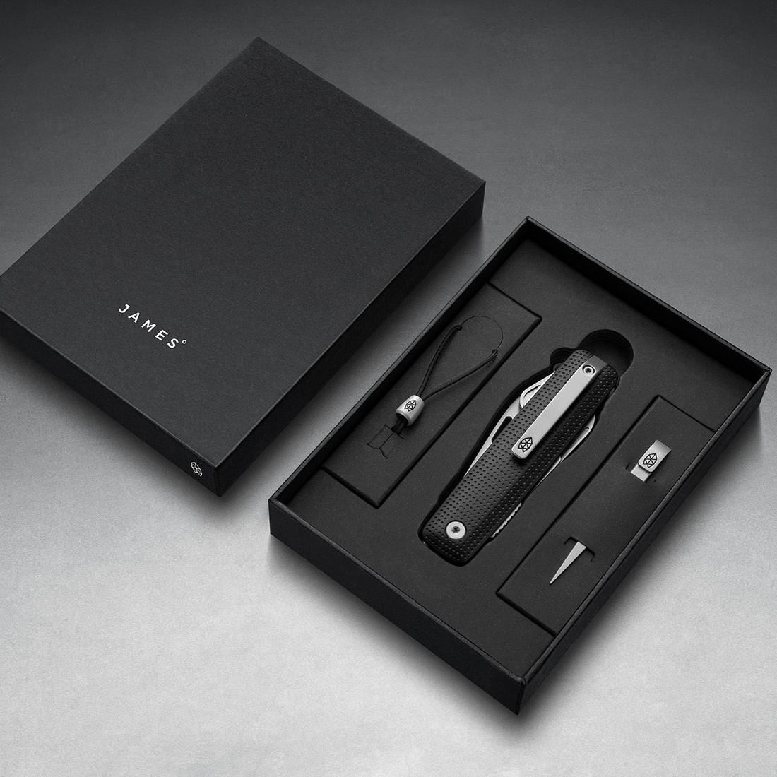 Helton in Black + Stainless in its box with lanyard and bead, top-down view