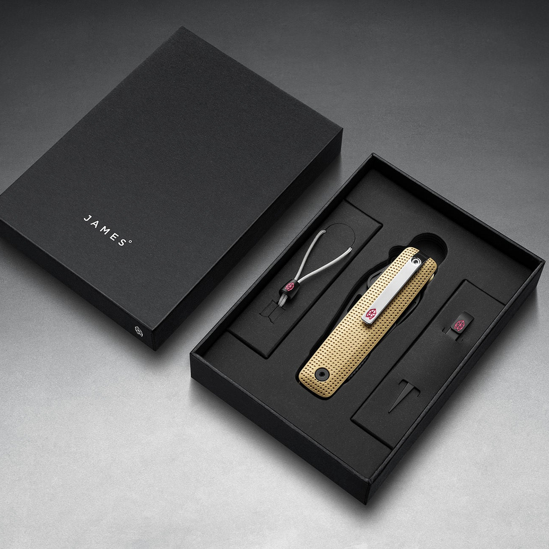 Helton in Buttermilk + Black in its box with lanyard and bead, top-down view
