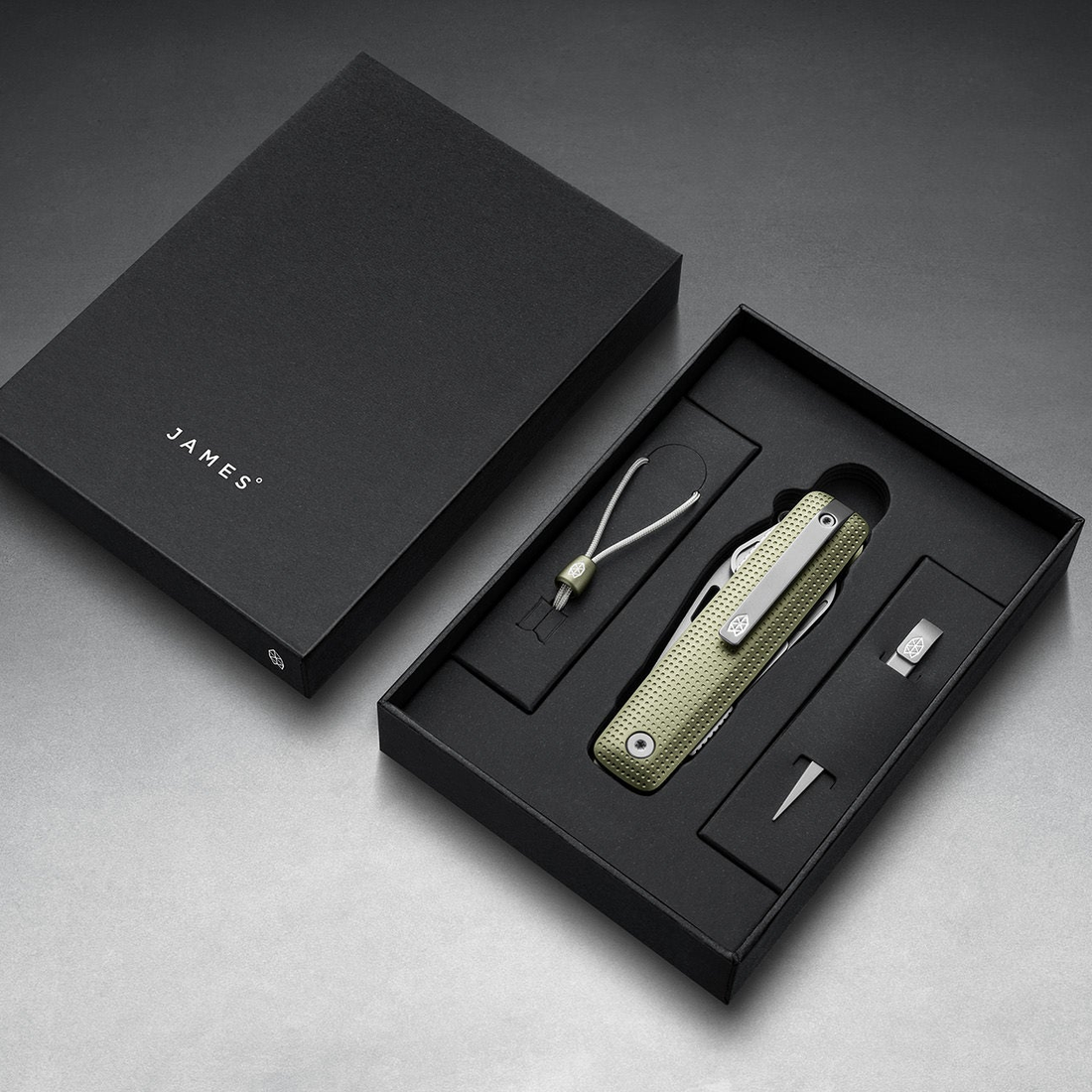 Helton in Grove + Stainless in its box with lanyard and bead, top-down view