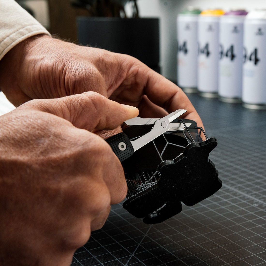 Hands using the Helton scissors to trim a black printed part on a workbench