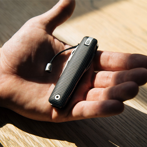 Helton multitool resting in an open palm with the lanyard attached