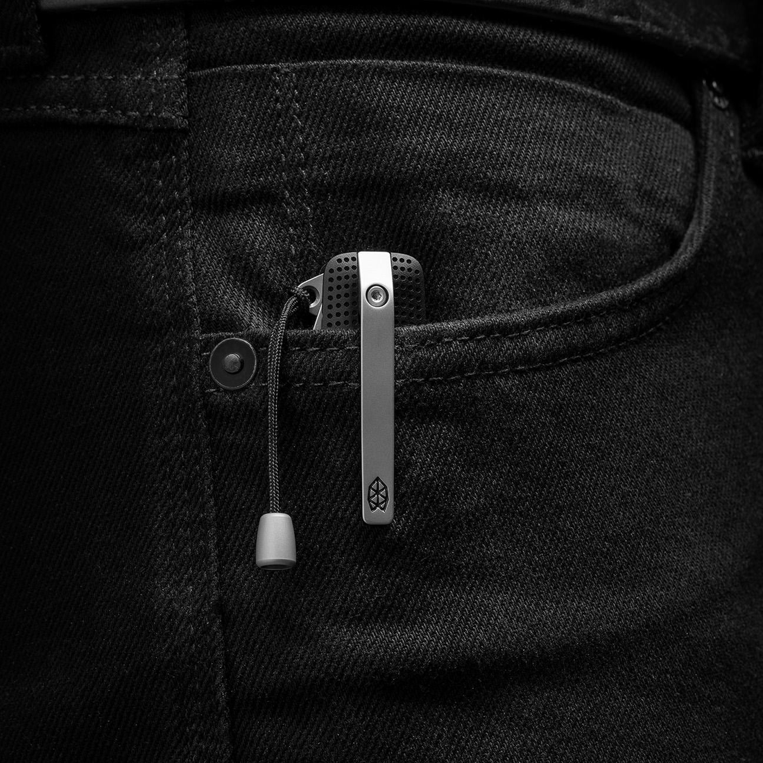 Helton multitool clipped in a jeans pocket with the lanyard bead hanging out