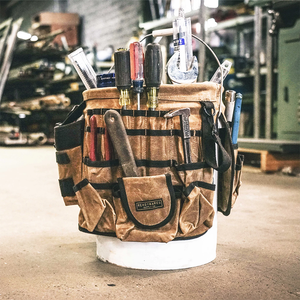 Readywares Waxed Canvas Tool Bucket Organizer, loaded with screwdrivers, wrench, and hammer in workshop