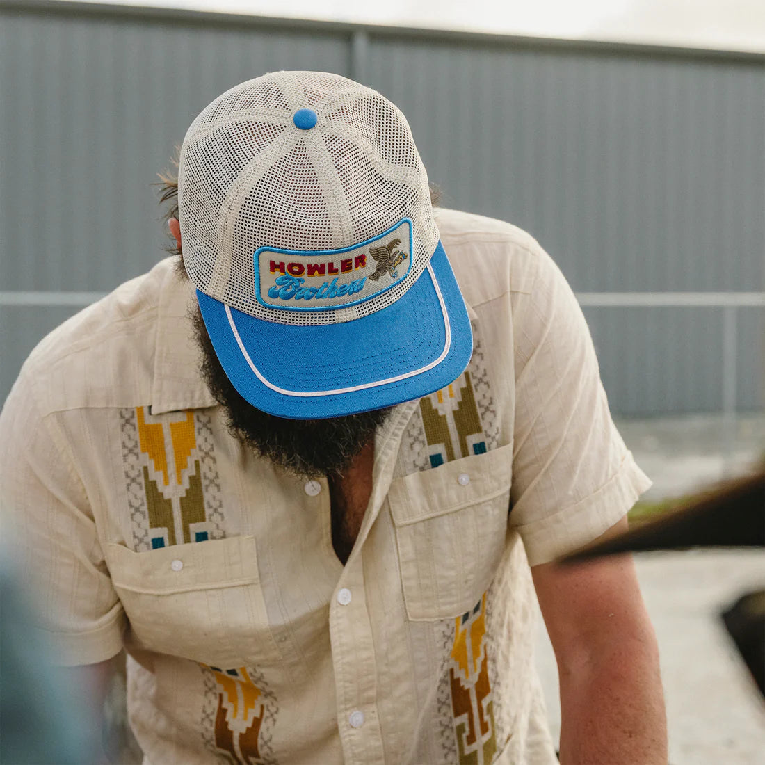 Man wearing Howler Brothers Osprey Prey Feedstore Snapback in Stone Blue – men's retro mesh trucker hat with embroidered patch and rope trim bill