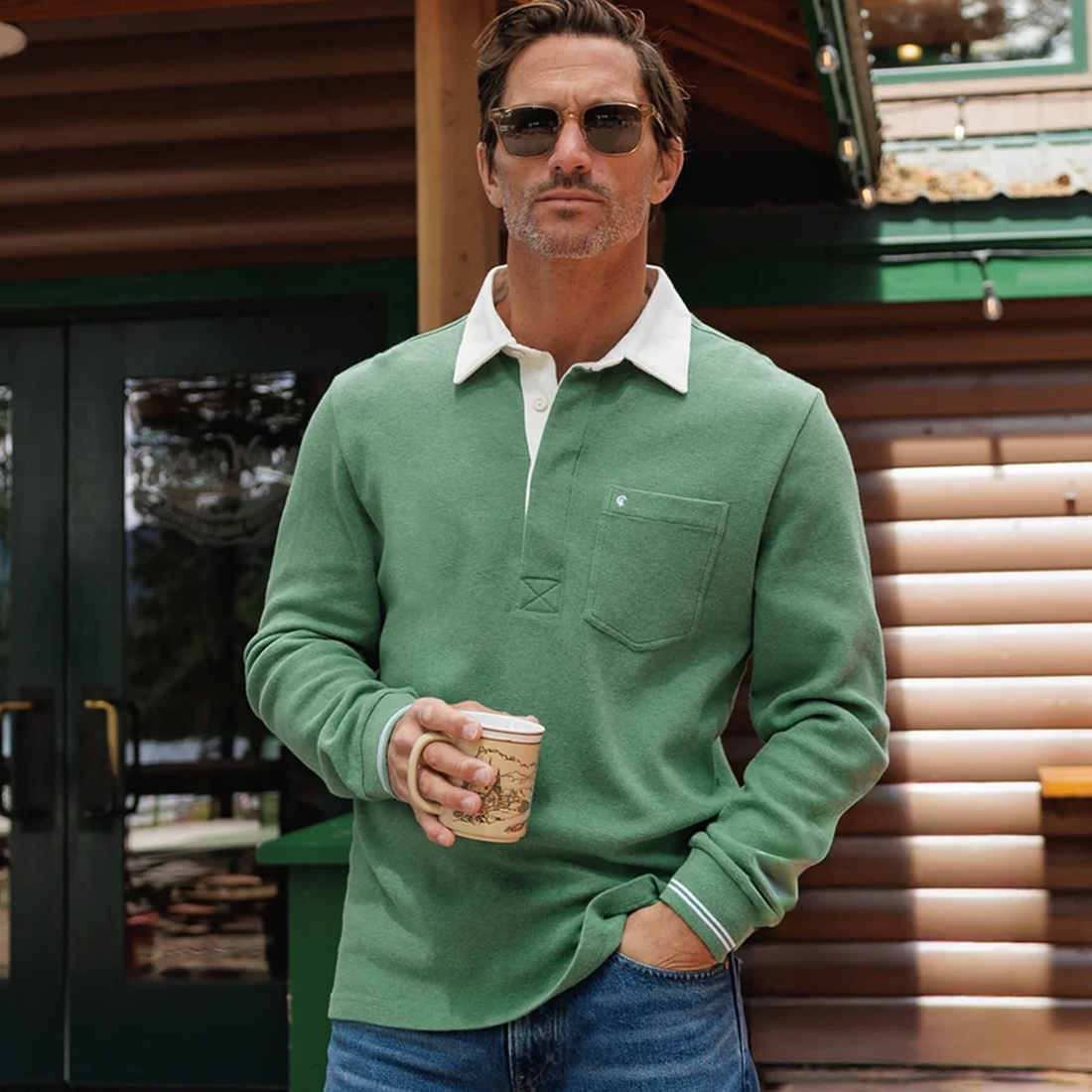 Man wearing Waffle Rugby Shirt in Heather Green holding coffee mug outside a cabin - The Simple Man