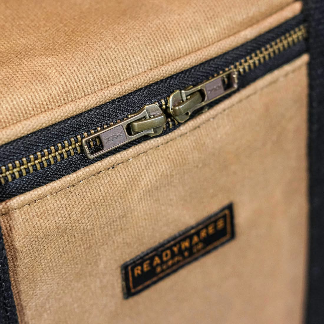 Close-up of the metal zipper and brand patch on the waxed canvas cooler bag, The Simple Man