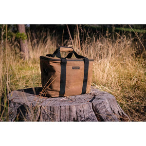 Waxed canvas cooler bag sitting on a tree stump in tall grass outdoors, The Simple Man
