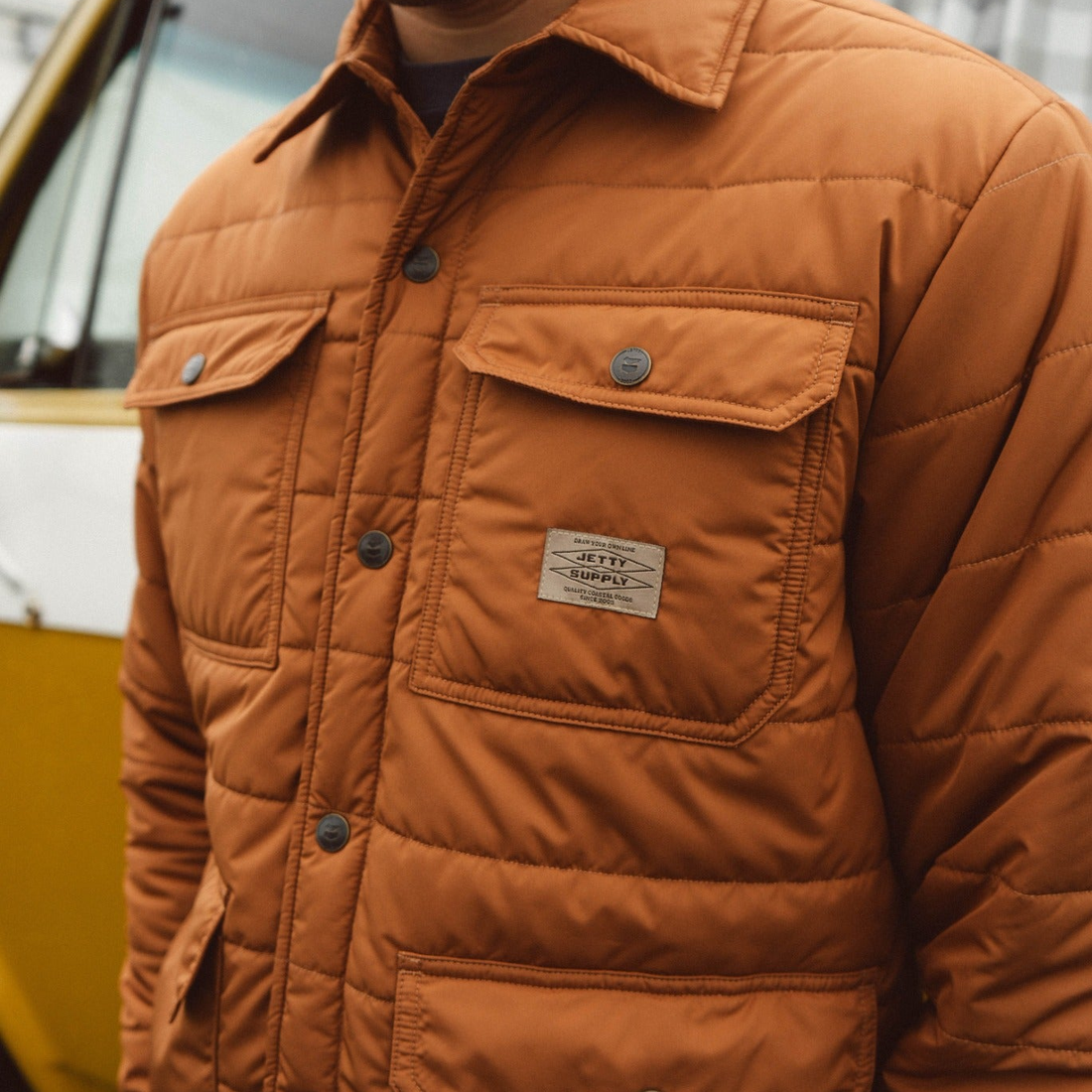 Close up of the Windward puffer jacket snap chest pocket and woven label, detail view
