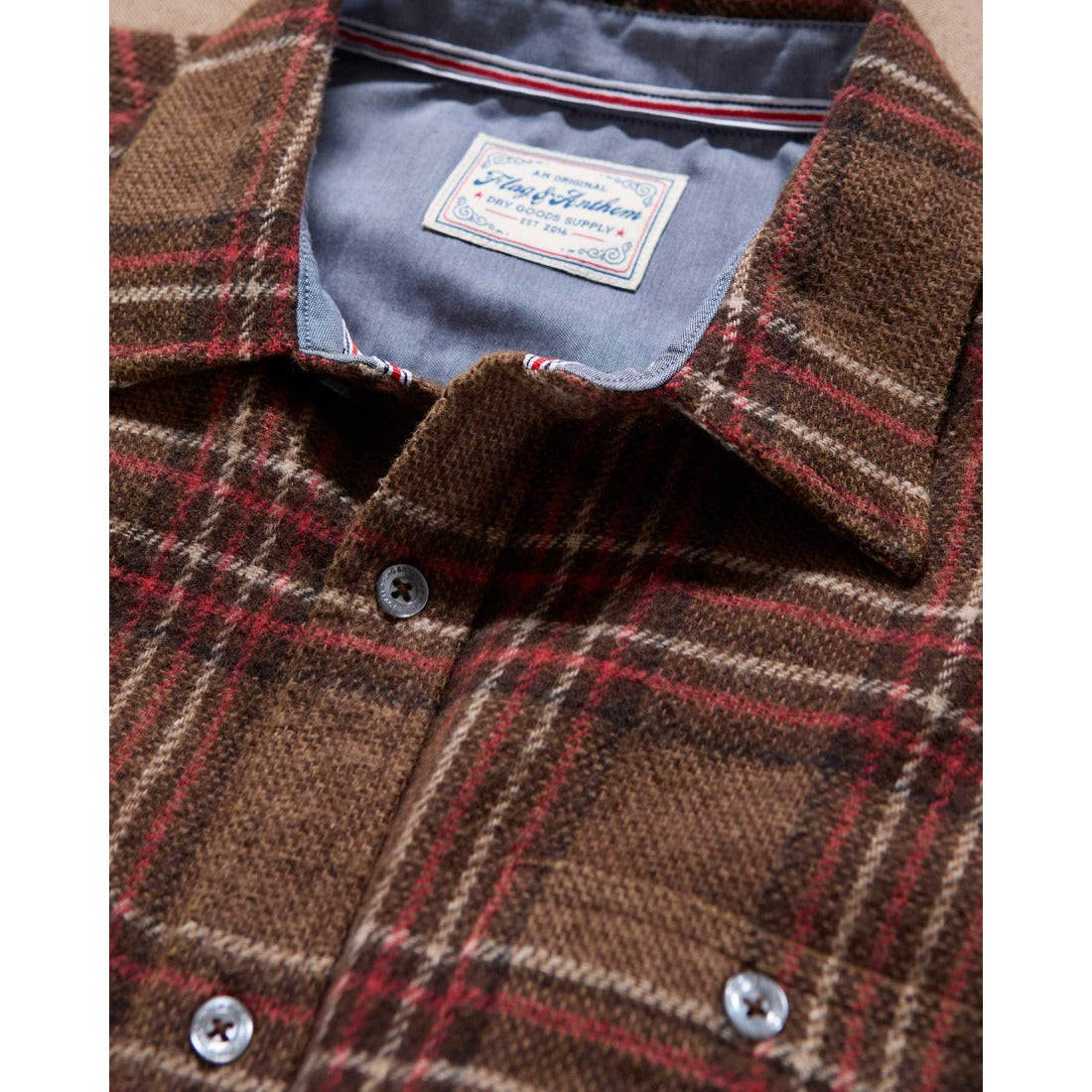 Close-up of the flannel shirt collar showing the contrast lining and brown and red plaid