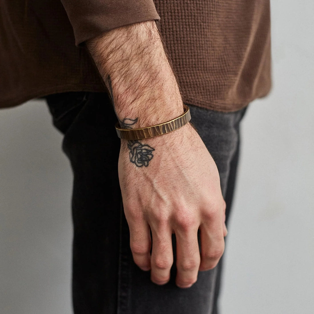 Men’s wrist wearing the brass Bessemer cuff with work patina finish, showing hammered texture and natural wear.