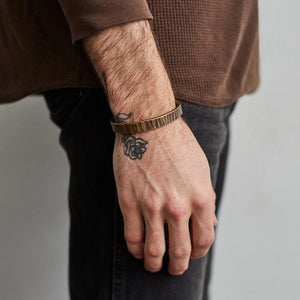 Men’s wrist wearing the brass Bessemer cuff with work patina finish, showing hammered texture and natural wear.