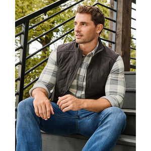 Charcoal diamond-quilted vest layered over a plaid button-down with jeans, outdoors