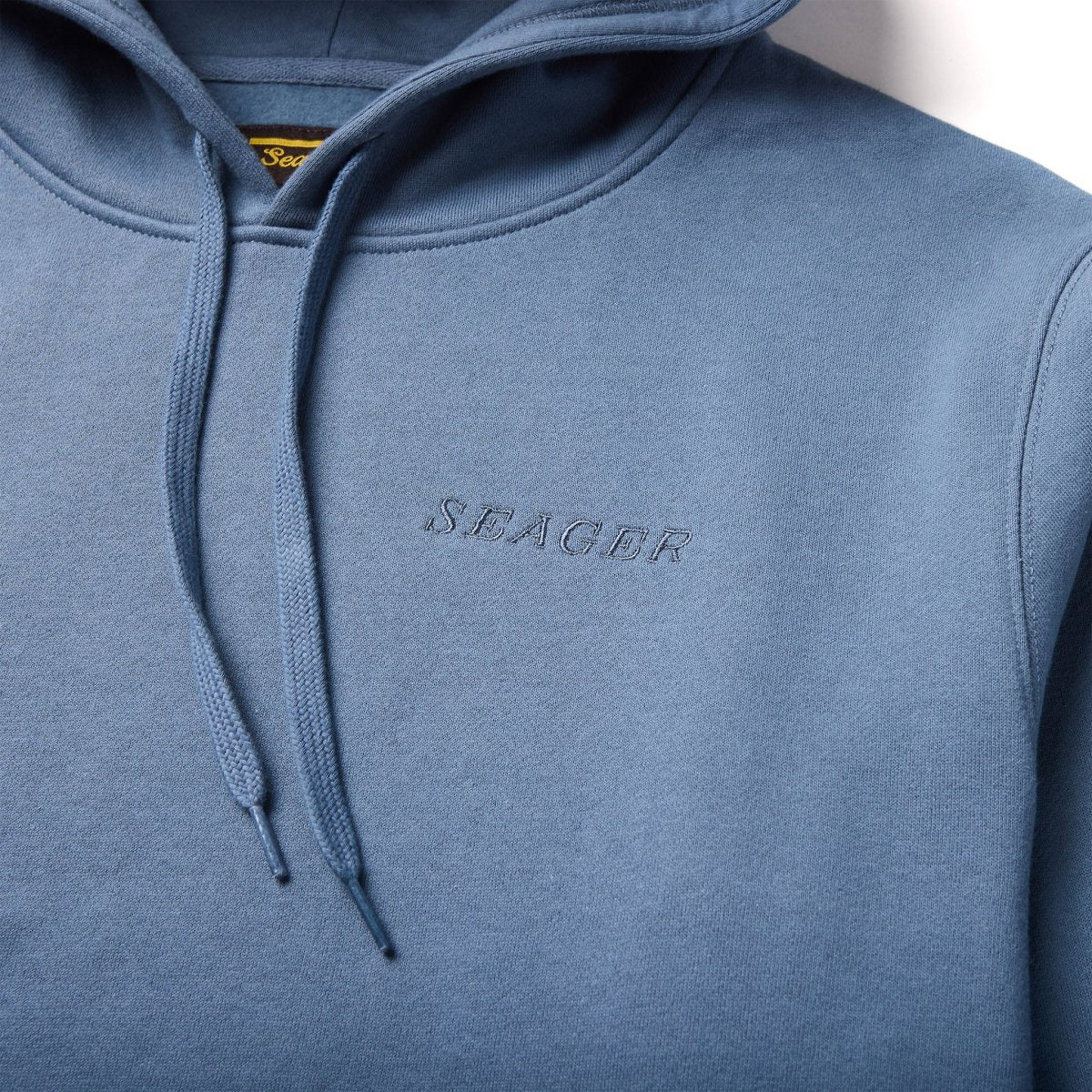 Close-up of Seager petrol blue hoodie showing embroidered logo and drawstrings – durable men's mid-weight hoodie from The Simple Man