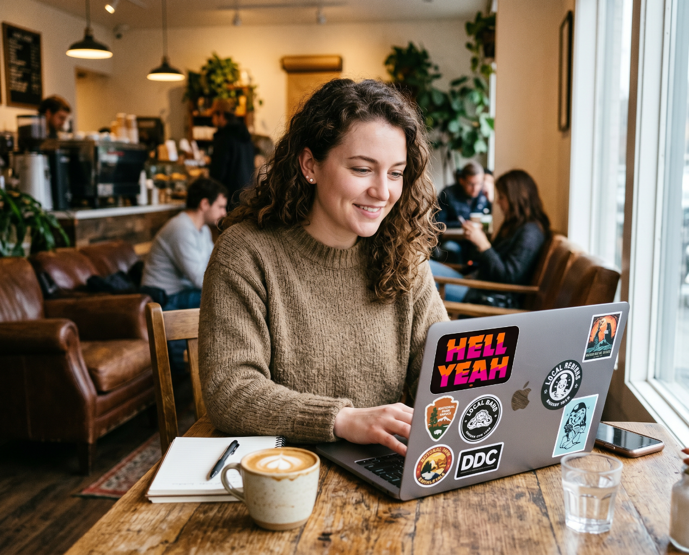 Woman using a laptop with stickers in a cozy café setting