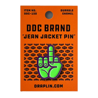 Fluorescent green on purple enamel middle finger pin from Draplin Design Co. Bold, durable, gift-ready on DDC card. Ships from The Simple Man in Omaha.