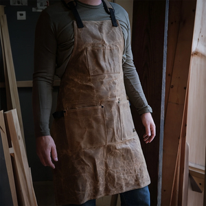 Man wearing Readywares Deluxe Waxed Canvas Utility Apron in workshop — 16oz waxed canvas apron with tool pockets and adjustable straps