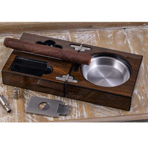 Folding walnut cigar ashtray set open with cigar resting — stainless steel ash reservoir guillotine cutter and punch cutter on wood surface