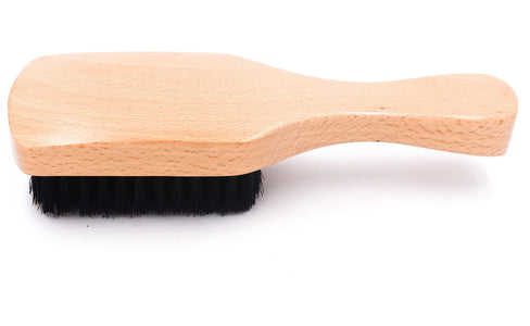 A boar bristle hairbrush with a natural beechwood handle shown from the side on a white background