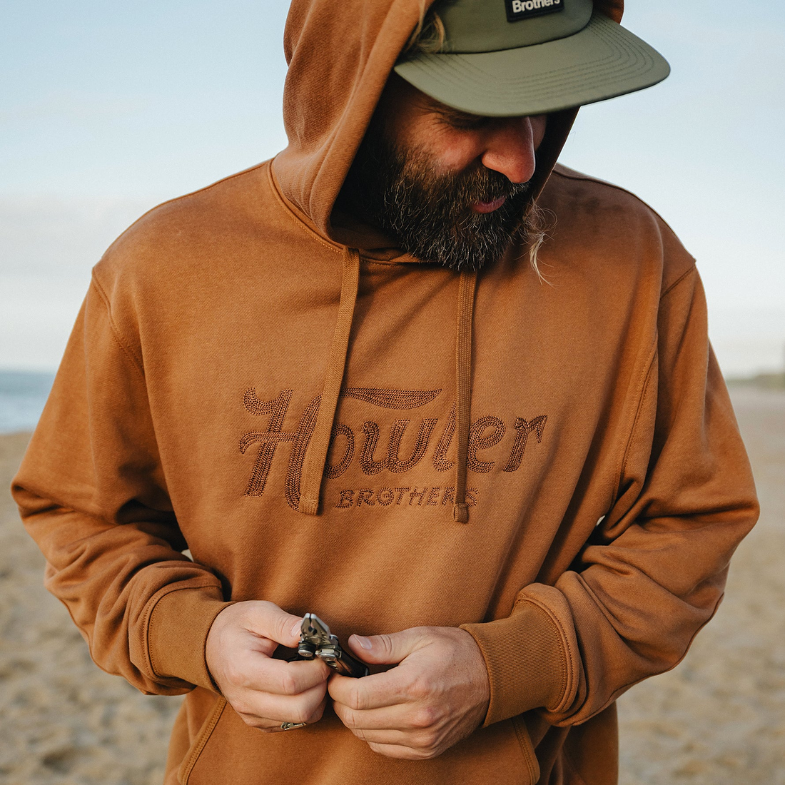 Man in Workbench Trade hoodie and cap on the beach
