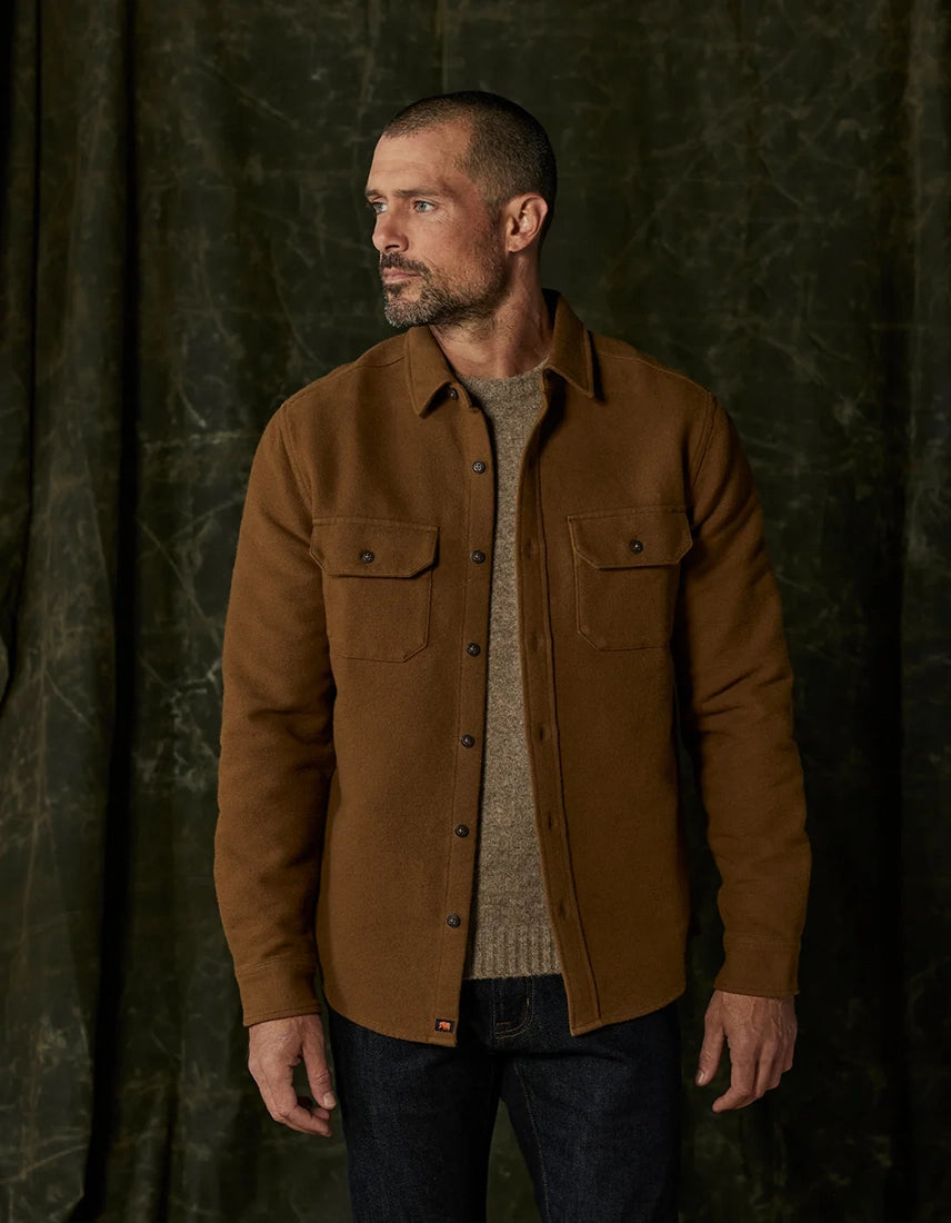 The Normal Brand Heavyweight Chamois Overshirt in gold worn over a crewneck sweater, showing dual chest pockets and button closure — from The Simple Man men’s shop.