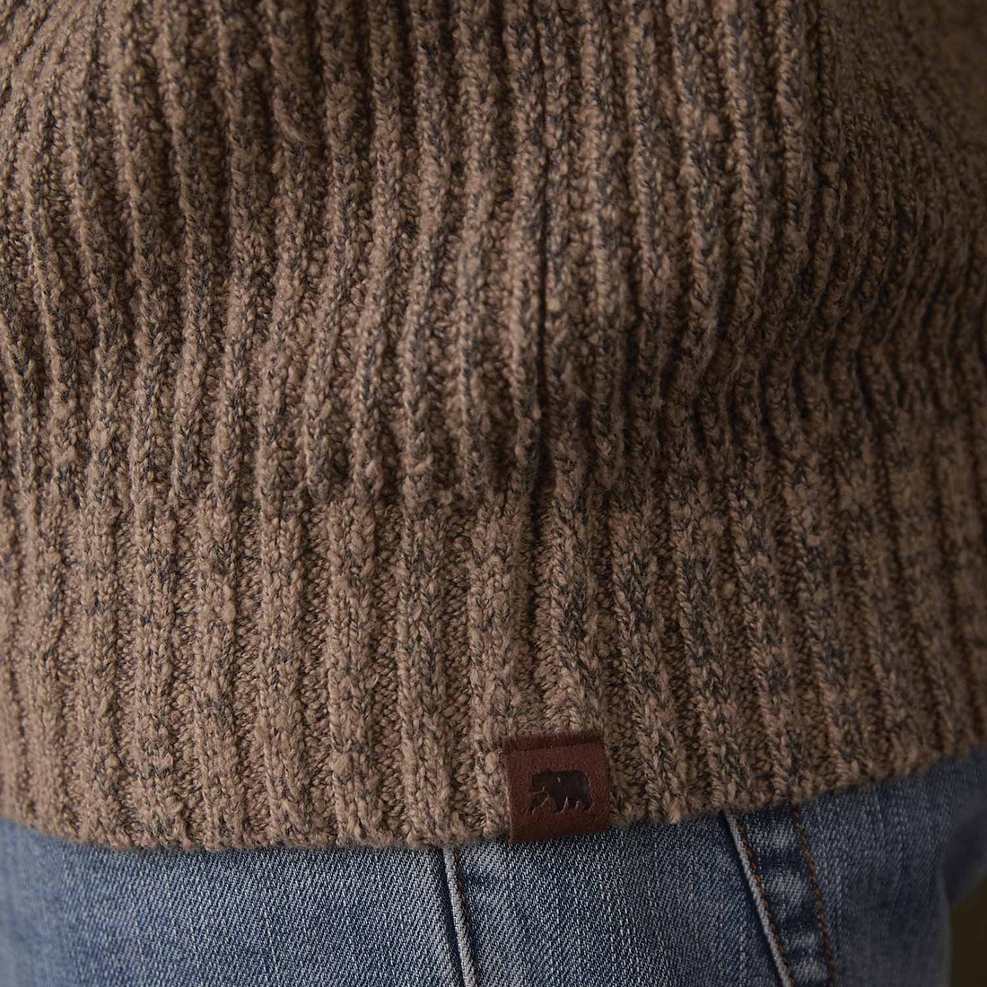 Close up of rib hem and leather bear tag on Taupe boucle popover sweater