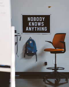 Nobody Knows Anything camp flag hanging in a modern office workspace