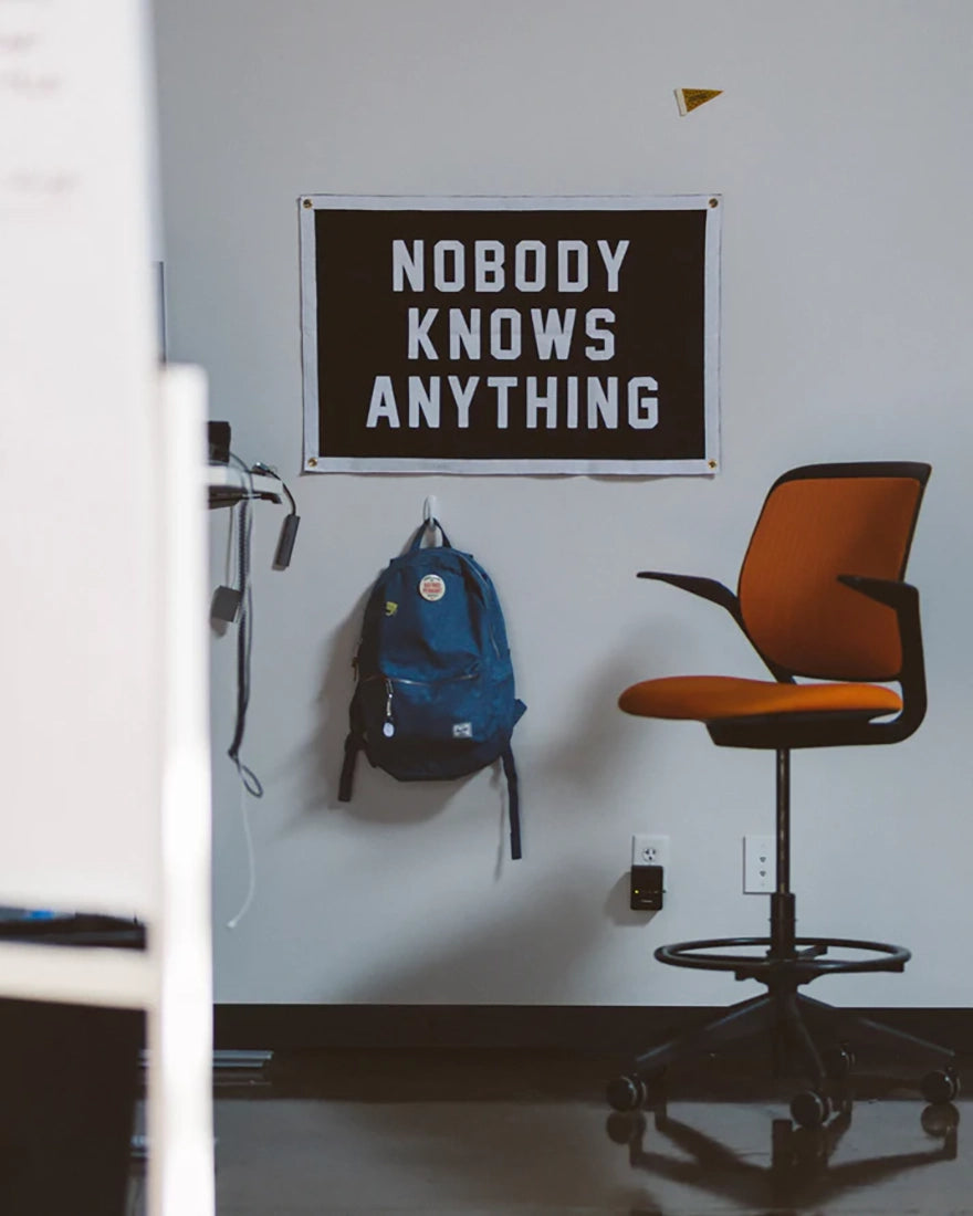 Nobody Knows Anything camp flag hanging in a modern office workspace