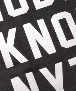 Close-up of Nobody Knows Anything camp flag showing white lettering on black wool felt