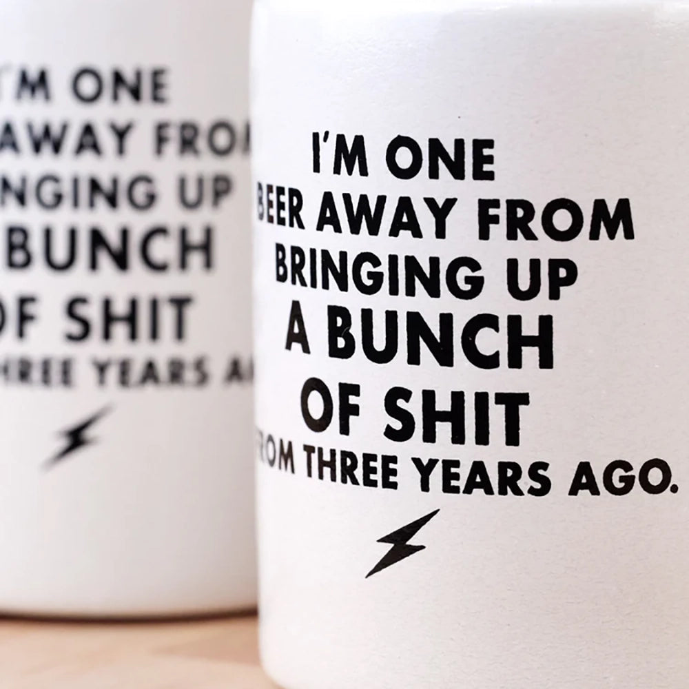 Close-up of the Vintage “One Beer Away” Koozie showing the bold black text printed on the white foam sleeve, sold by The Simple Man in Omaha.