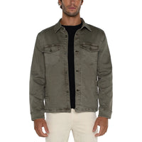 Man wearing a green denim jacket over a black shirt on a white background