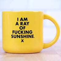 I Am a Ray of Fucking Sunshine yellow ceramic coffee mug front view showing bold black text on white background by Meriwether