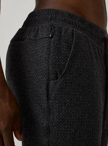 Model Wearing Restoration joggers in charcoal close up fabric detail view
