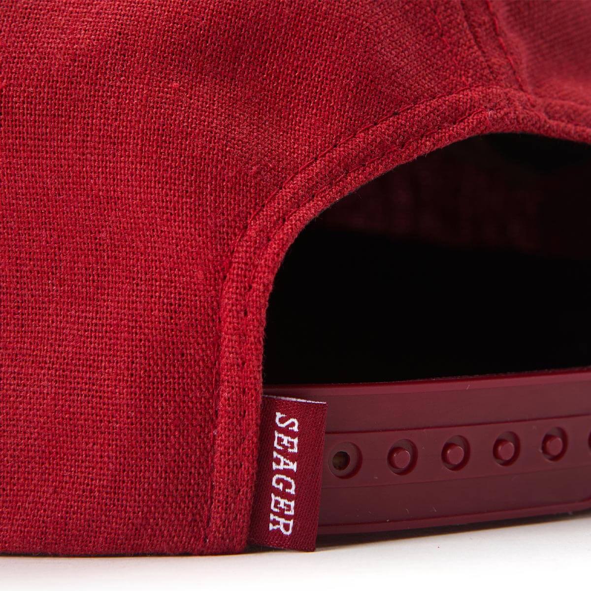 Detailed view of Seager tag and rear plastic snapback strap on red hemp cap