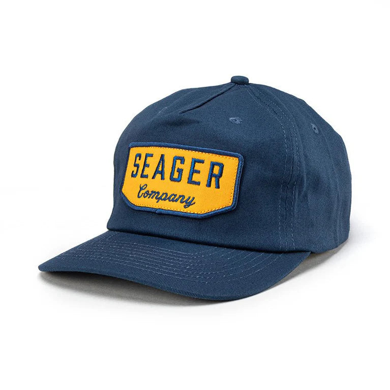 Angled front view of Seager Wilson Snapback Hat in navy with yellow logo patch