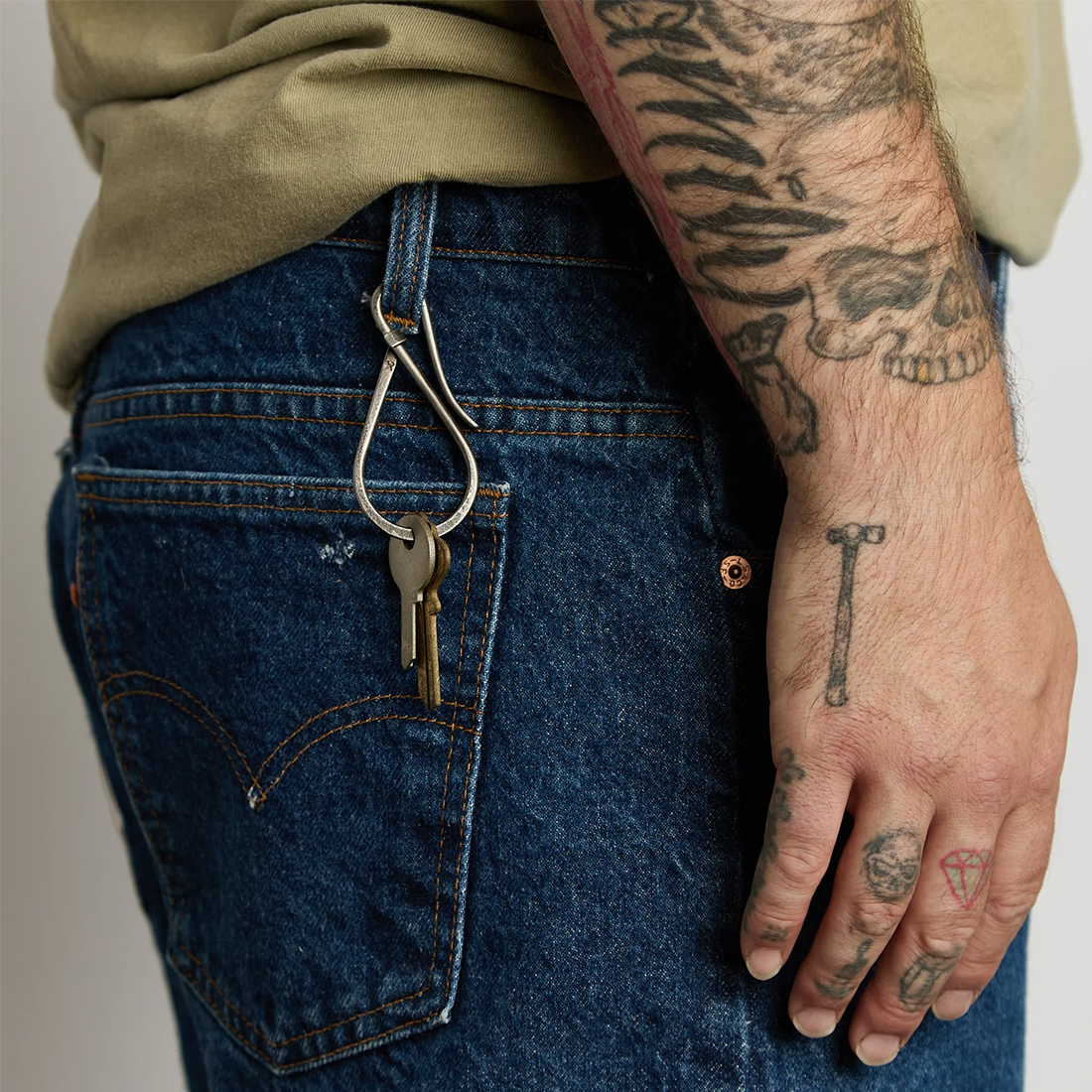 Brass Workshop Keyholder clipped to a belt loop on blue jeans with two keys hanging from it