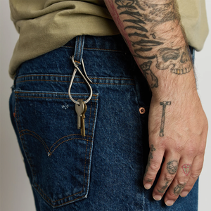 Brass Workshop Keyholder clipped to a belt loop on blue jeans with two keys hanging from it