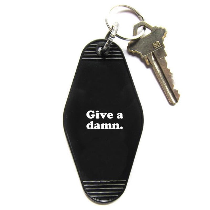Black Hotel style keychain with " Give a damn" printed in white
