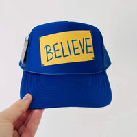 Ted Lasso Believe sign on a royal blue trucker cap